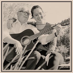 Arthur und Janna Ise Arthur und Janna Ise sitzen zusammen und spielen Gitarre im Freien, lächelnd und entspannt.