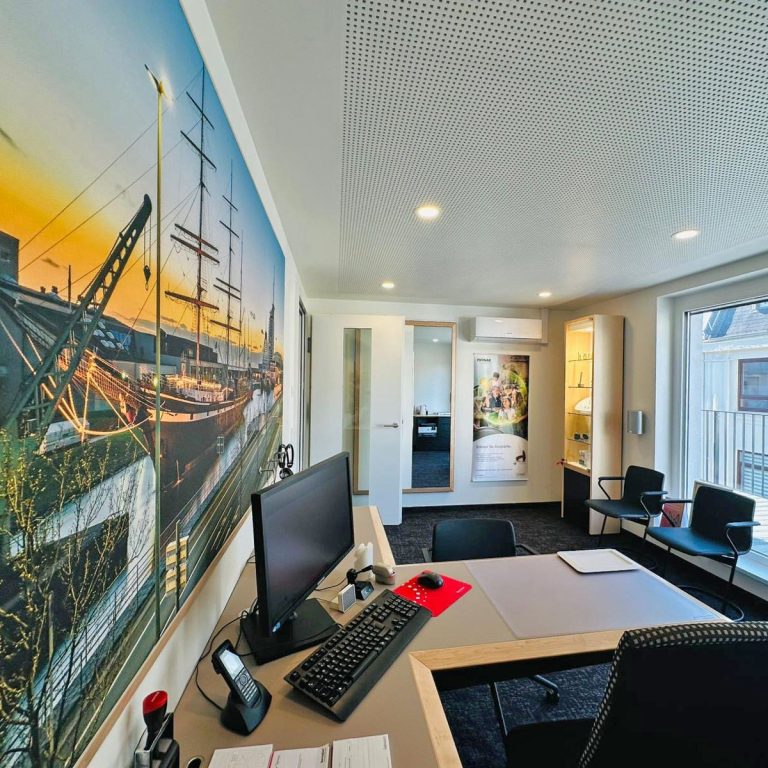Moderner Anpaßraum von ISE Hörgeräte Moderne Büroumgebung mit Wandbild eines Schiffs und hellem, einladendem Design.