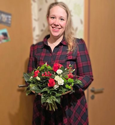 Herzlichen Glückwunsch Frau mit blonden Haaren hält einen bunten Blumenstrauß in der Hand.