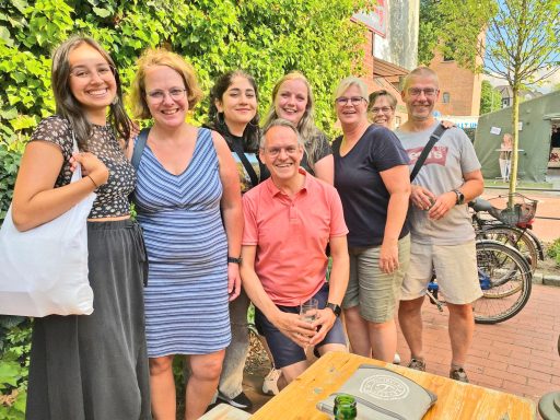 ISE und Fielmann Mitarbeiter zusammen Gruppe von sieben Personen lächelt vor grünen Pflanzen, am Tisch im Freien.