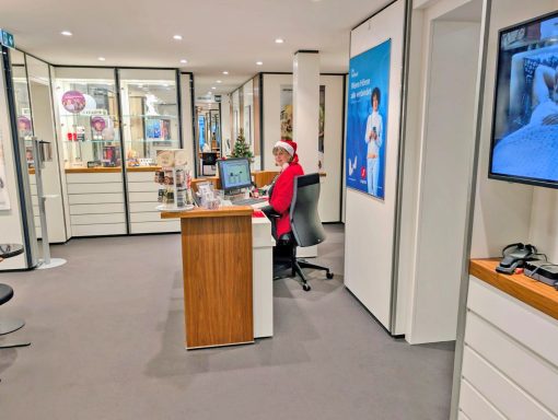 Büro mit einem Schreibtisch, einem Computer und einer Person in rotem Outfit.