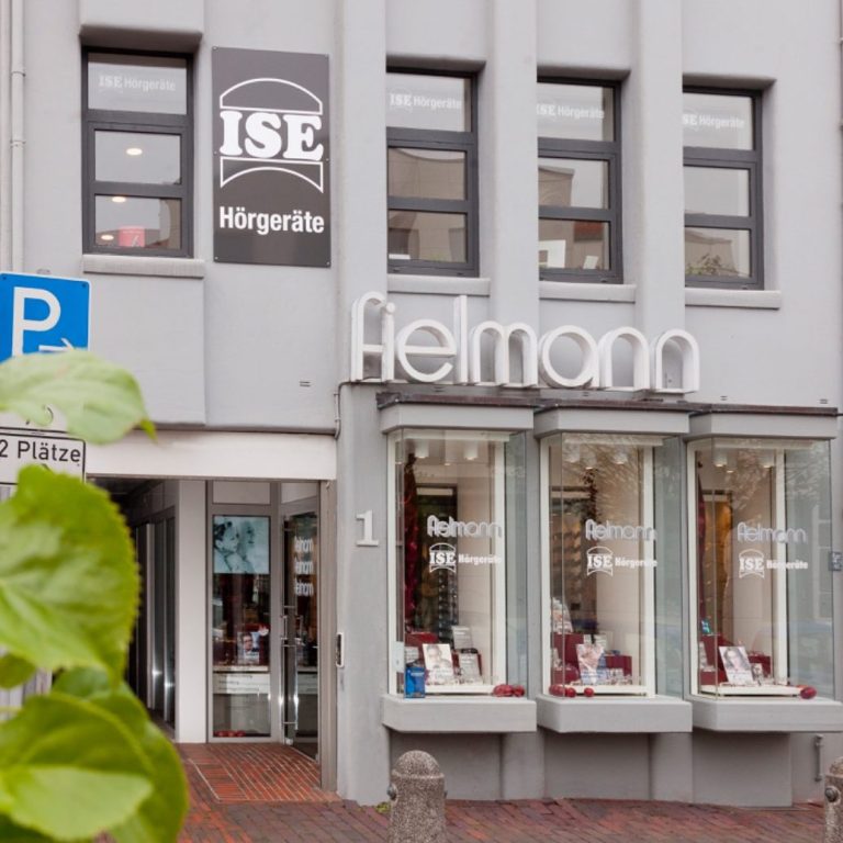 ISE Hörgeräte Filiale Jever Geschäftsfront mit dem Namen "Fielmann" und "ISE Hörgeräte" mit Schaufenstern, die Ware präsentieren.